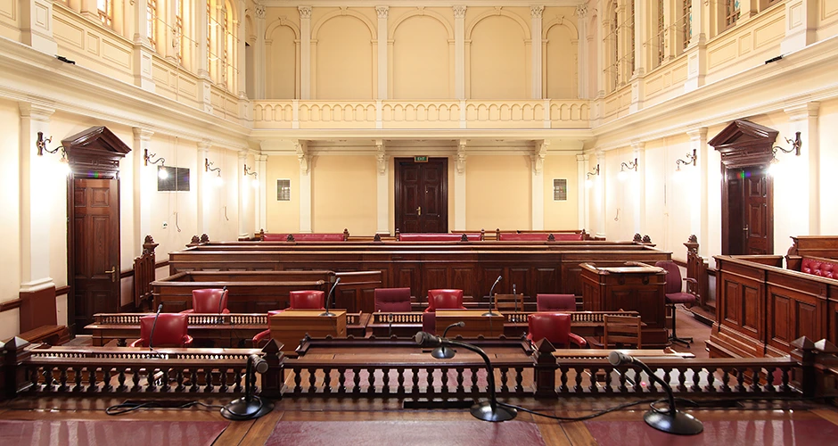 South African courtroom with a classic wooden interior, desks, and seating areas prepared for legal proceedings.