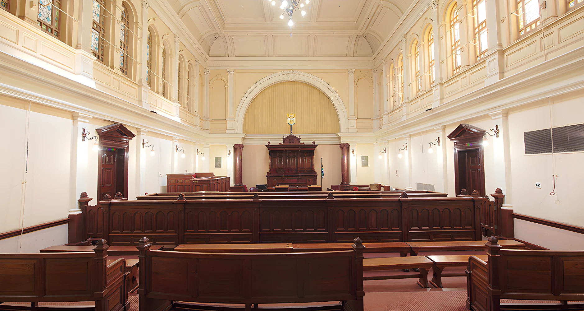Interior of a South African courtroom with wooden benches, a judge's stand, and elegant architectural details.